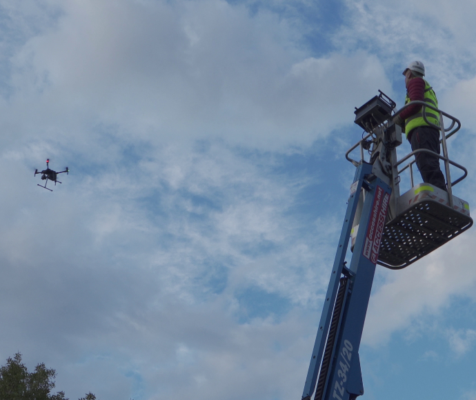 A pilot operating a drone from an elevated cherry picker
